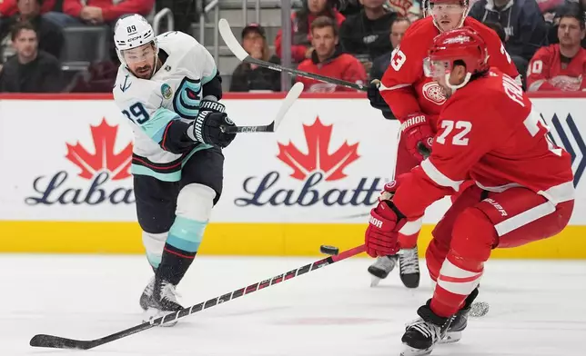 Seattle Kraken center Frederick Gaudreau (89) shoots over the stick of Detroit Red Wings defenseman Justin Faulk (72) to score in the second period of an NHL hockey game Friday, Oct. 9, 2026, in Detroit. (AP Photo/Paul Sancya)