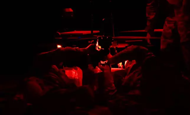 In this undated image from video provided by the Ukrainian 34th Separate Marine Brigade "Borysfen" on Oct. 4, 2026, Ukrainian soldiers at an undisclosed location in the Kherson region of Ukraine attach a parcel of supplies to a drone before a flight to the Russian-occupied city of Oleshky. (Ukrainian 34th Separate Marine Brigade "Borysfen" via AP)