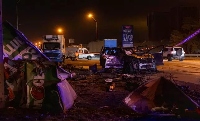Emergency workers clear debris and damaged road infrastructure near a destroyed car following a Russian overnight strike in Kyiv, Ukraine, Tuesday, Oct. 27, 2026. (AP Photo/Dan Bashakov)