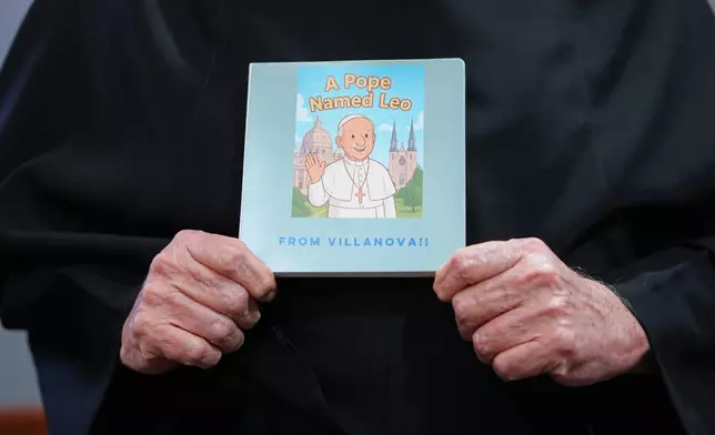 Villanova University President Rev. Peter M. Donohue holds a book during an interview in his office Wednesday, Oct. 21, 2026, in Villanova, Pa. (AP Photo/Matt Rourke)
