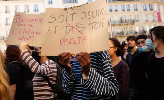 A students holds a board reading in French "Be young and shut/revolt up", during a demonstration against under-resourced schools, in Paris, Tuesday, Oct. 6, 2026. (AP Photo/Teresa Suarez)