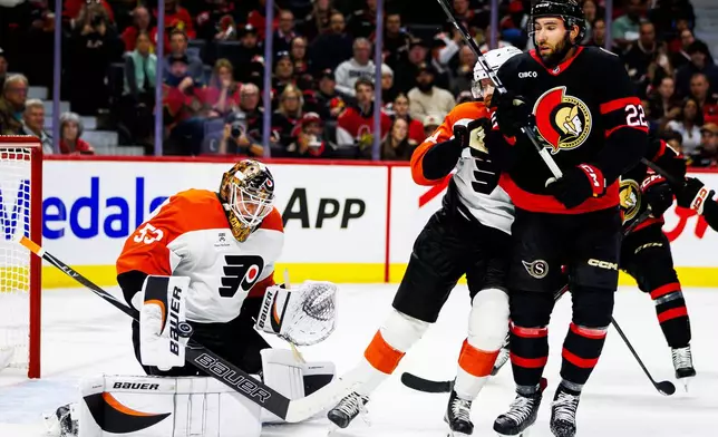 Philadelphia Flyers goaltender Joseph Woll (53) makes a save as Ottawa Senators' Michael Amadio (22) creates traffic in front during the second period of an NHL hockey game in Ottawa, Ontario, Thursday, Oct. 8, 2026. (Keito Newman/The Canadian Press via AP)