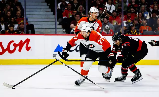 Philadelphia Flyers' Noah Cates (27) skates with the puck as Ottawa Senators' Dylan Cozens (24) reaches to block him during the second period of an NHL hockey game in Ottawa, Ontario, Thursday, Oct. 8, 2026. (Keito Newman/The Canadian Press via AP)