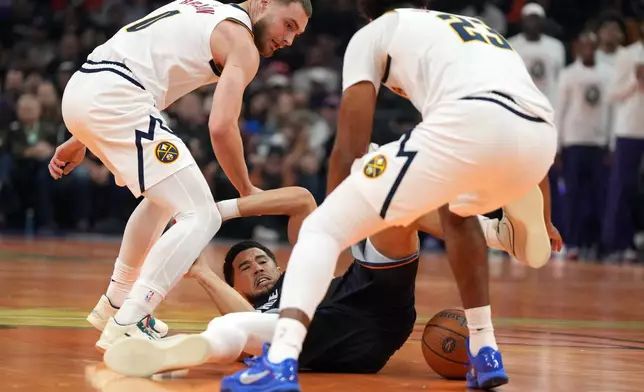 Phoenix Suns guard Devin Booker, bottom, has the ball stolen from him by Denver Nuggets guard Christian Braun (0) and forward Cameron Johnson (23) during the first half of an NBA Cup basketball game, Friday, Oct 30, 2026, in Phoenix. (AP Photo/Rick Scuteri)