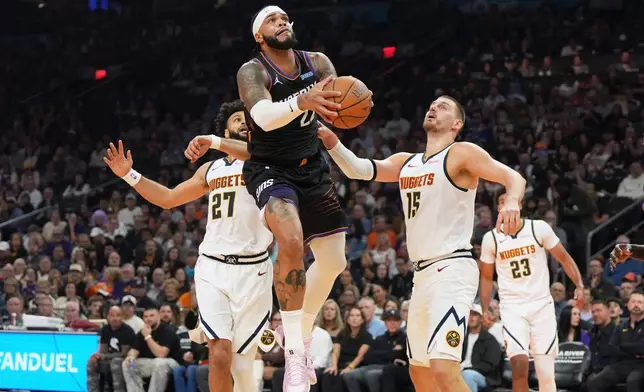 Phoenix Suns forward Miles Bridges, center, drives between Denver Nuggets guard Jamal Murray (27) and center Nikola Jokic (15) during the first half of an NBA Cup basketball game, Friday, Oct 30, 2026, in Phoenix. (AP Photo/Rick Scuteri)