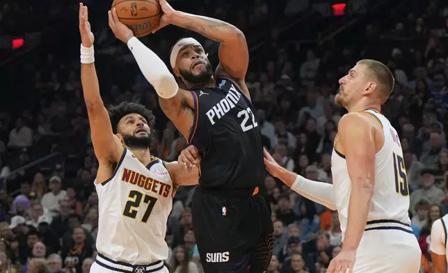 Phoenix Suns forward Miles Bridges, center, drives between Denver Nuggets guard Jamal Murray (27) and center Nikola Jokic (15) during the first half of an NBA Cup basketball game, Friday, Oct 30, 2026, in Phoenix. (AP Photo/Rick Scuteri)