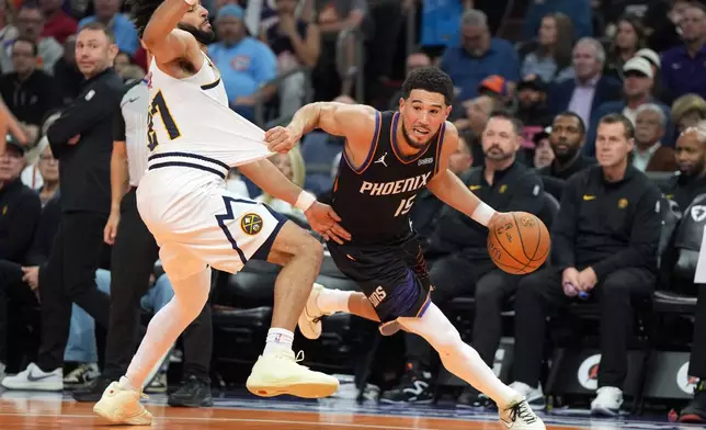 Phoenix Suns guard Devin Booker (15) drives around Denver Nuggets guard Jamal Murray, left, during the first half of an NBA Cup basketball game, Friday, Oct 30, 2026, in Phoenix. (AP Photo/Rick Scuteri)