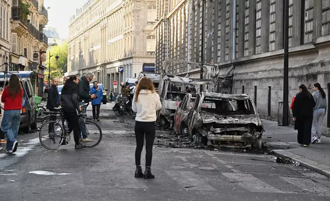 People look at charred cars the day after a demonstration against rising living costs, joining students' grievances, in Paris, Sunday, Oct. 18, 2026. (AP Photo/Emma Da Silva)