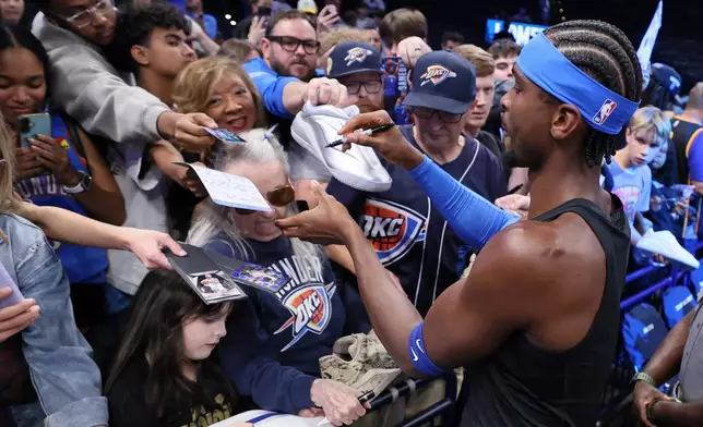 Oklahoma City Thunder guard Shai Gilgeous-Alexander, right, signs autographs for fans before an NBA basketball game against the Denver Nuggets, Thursday, Oct. 22, 2026, in Oklahoma City. (AP Photo/Nate Billings)