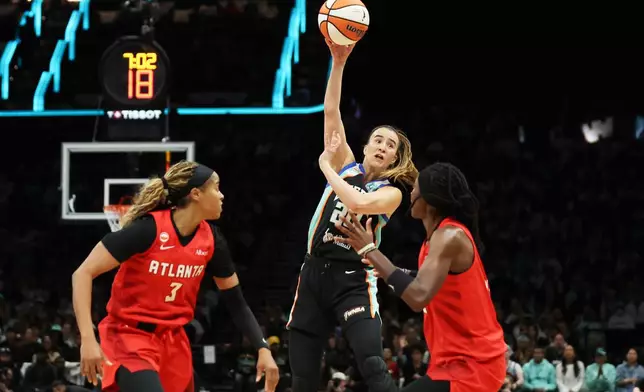 New York Liberty guard Sabrina Ionescu, center, passes the ball against Atlanta Dream guards Jordin Canada (3) and Rhyne Howard, right, during the first half of Game 3 of the WNBA basketball semifinals, Friday, Oct. 9, 2026, in New York. (AP Photo/Heather Khalifa)