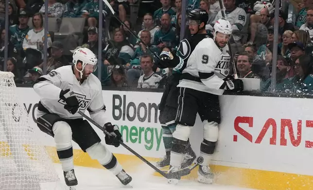 Los Angeles Kings defenseman Joel Edmundson (6) reaches for the puck next to right wing Adrian Kempe (9) and San Jose Sharks left wing Mason Marchment (27) an NHL hockey game, Saturday, Oct. 3, 2026, San Jose, Calif. (AP Photo/Jeff Chiu)