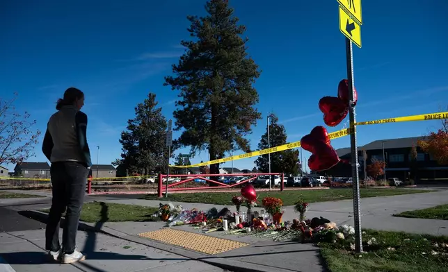 A person stands near a makeshift memorial outside Silver Rail Elementary in Bend, Ore., Friday, Oct. 16, 2026, a day after a deadly shooting. (AP Photo/Joe Kline)
