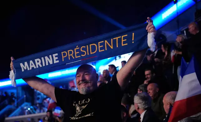 A man holds a scarf reading 'Marine for president' during the 19th Congress of the French far-right party, the National Rally, in Orleans, France, Sunday, Oct. 25, 2026. (AP Photo/Teresa Suarez)