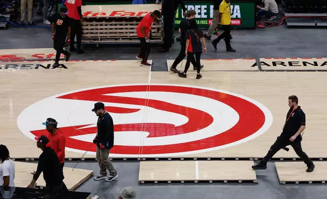 Workers quickly assemble the Atlanta Hawks court after Game 4 between WNBA Finals before the Hawks host the Houston Rocket in the home-opener NBA basketball game, Saturday, Oct. 24, 2026, in Atlanta. (AP Photo/Erik S. Lesser)