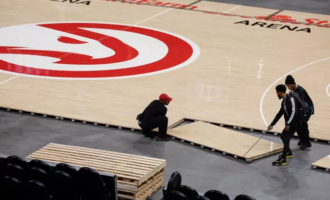 Workers quickly assemble the Atlanta Hawks court after Game 4 between WNBA Finals before the Hawks host the Houston Rocket in the home-opener NBA basketball game, Saturday, Oct. 24, 2026, in Atlanta. (AP Photo/Erik S. Lesser)