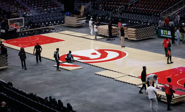 Workers quickly assemble the Atlanta Hawks court after Game 4 between WNBA Finals before the Hawks host the Houston Rocket in the home-opener NBA basketball game, Saturday, Oct. 24, 2026, in Atlanta. (AP Photo/Erik S. Lesser)