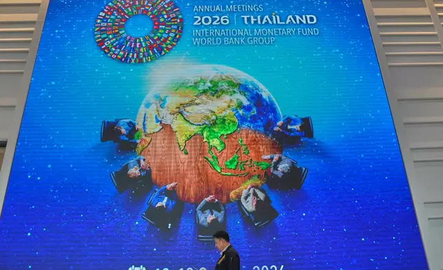 A man walks in front of giant billboard at the Queen Sirikit National Convention Center ahead of the annual meetings of the International Monetary Fund (IMF) and the World Bank Group in Bangkok, Thailand, Friday, Oct. 9, 2026. (AP Photo/Sakchai Lalit)