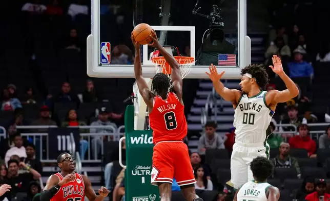 Chicago Bulls forward Caleb Wilson (8) dunks the basketball while defended by Milwaukee Bucks center Jericho Sims (00) during the second half of an NBA preseason basketball game, Wednesday Oct. 14, 2026, in Milwaukee. (AP Photo/Ross Harried)