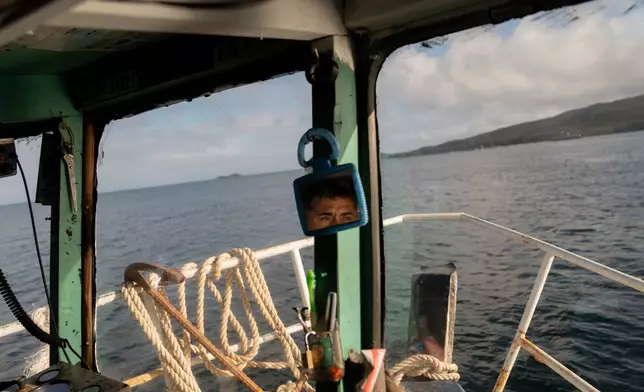Daniel Arturo Caniullan Huentel, leader of the Indigenous Mapuche Pu Wapi community and a shellfish fisher, sails near a salmon farm located close to a sea urchin nursery and fishing grounds in the Guaitecas Archipelago, Chile, Thursday, May 22, 2025. (AP Photo/Adriana Thomasa)