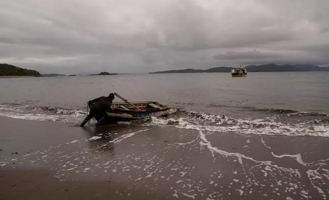Daniel Arturo Caniullan Huentel, leader of the Indigenous Mapuche Pu Wapi community and a shellfish fisher, pushes a boat into the water before rowing out to his fishing boat in the Guaitecas Archipelago, Chile, Thursday, May 22, 2025. (AP Photo/Adriana Thomasa)