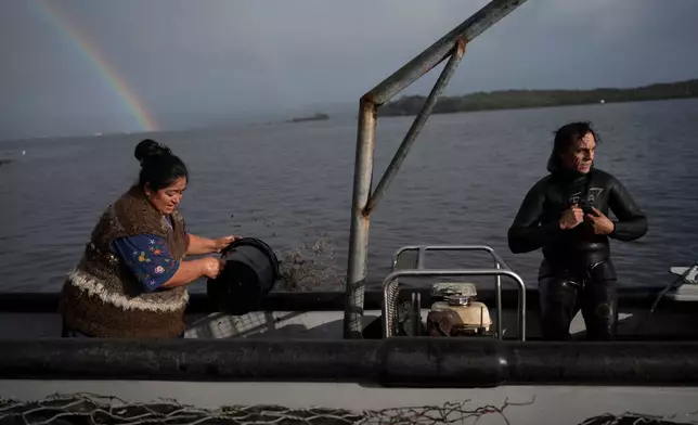 Yesica Fabiana Leviñanco, left, and her partner, Paulo Vera Perez, prepare for a fishing journey in Repollal, in the Guaitecas Archipelago, Chile, Wednesday, May 21, 2025. (AP Photo/Adriana Thomasa)