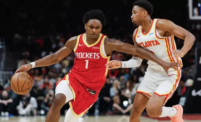 Houston Rockets guard Amen Thompson (1) drives against Atlanta Hawks guard Aaron Wiggins, right, during the first half of an NBA basketball game, Saturday, Oct. 24, 2026, in Atlanta. (AP Photo/Erik S. Lesser)