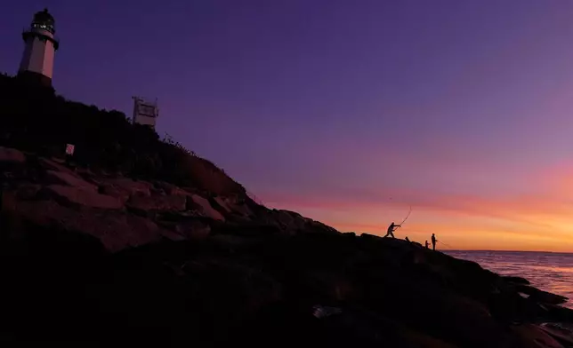 Fishermen cast for striped bass below the Montauk Point Lighthouse at dawn Saturday, Oct. 10, 2026, in Montauk, N.Y. (AP Photo/Robert F. Bukaty)