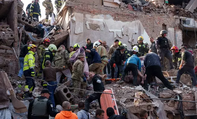 Locals and rescuers carry bodies of people, killed in a Russian missile strike on a residential building, in Pryluky, Ukraine, Wednesday, Oct. 7, 2026. (AP Photo/Evgeniy Maloletka)