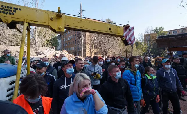 Locals keep silence standing next to a residential building destroyed in a Russian missile strike on Pryluky, Ukraine, Wednesday, Oct. 7, 2026. (AP Photo/Evgeniy Maloletka)