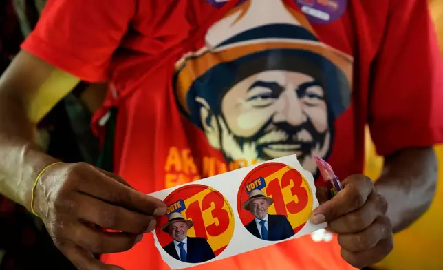 A supporter of Brazilian President Luiz Inacio Lula da Silva, who is running for reelection, holds campaign stickers bearing Lula's image and number 13 during a campaign event on streets in Brasilia, Brazil, Wednesday, Sept. 30, 2026. (AP Photo/Eraldo Peres)