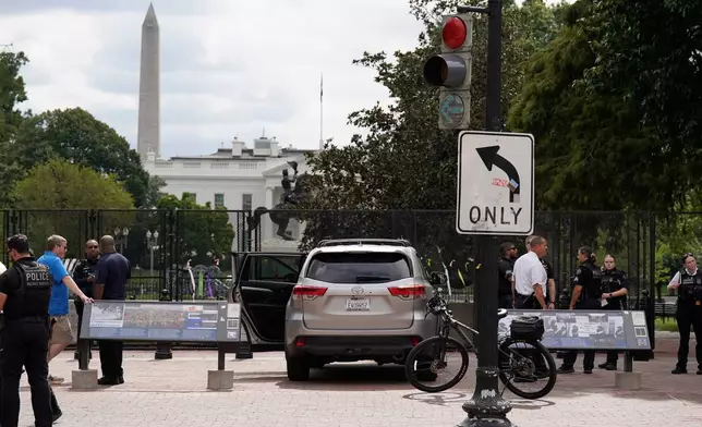U.S. Secret Service Police stand near a car that sits parked on a sidewalk near the White House after the driver was arrested, Saturday, Sept. 19, 2026, in Washington. (AP Photo/Jose Luis Magana)