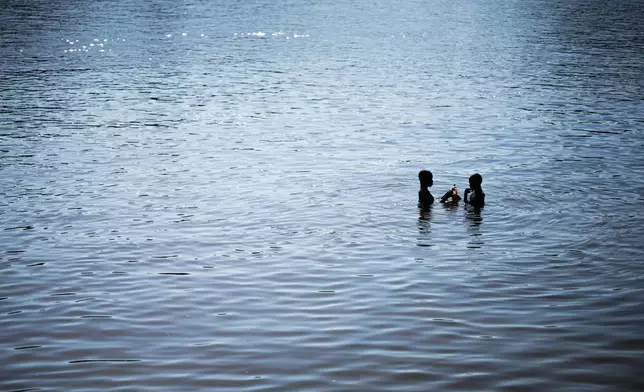 Two children take a bath in the morning in the Suriname River near Nieuw Aurora, Suriname, Wednesday, Sept. 30, 2026. (AP Photo/Ivan Valencia)