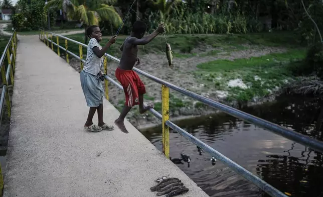 Children fish on a bridge in Nieuw Aurora, Suriname, Monday, Sept. 28, 2026. (AP Photo/Ivan Valencia)