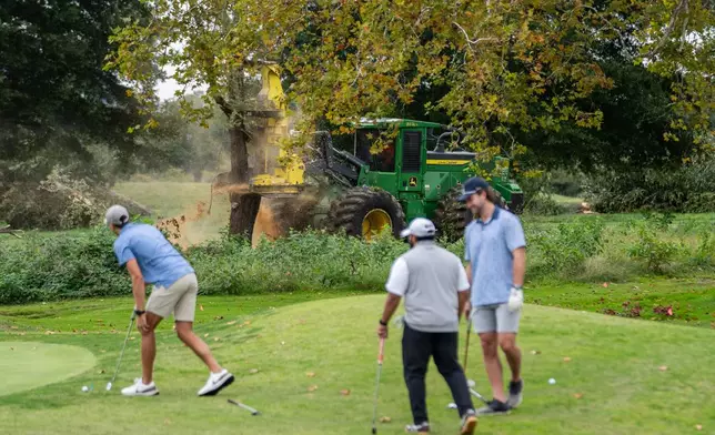 Golfers pass workers as the National Park Service begins cutting down trees at East Potomac Golf Links, Saturday, Oct. 10, 2026, in Washington. (AP Photo/Nathan Howard)
