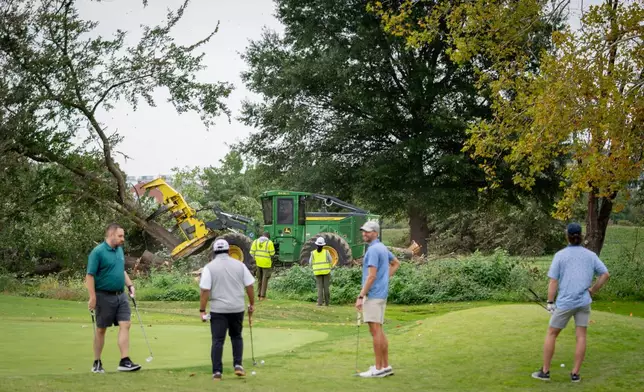 Golfers pass workers as the National Park Service begins cutting down trees at East Potomac Golf Links, Saturday, Oct. 10, 2026, in Washington. (AP Photo/Nathan Howard)