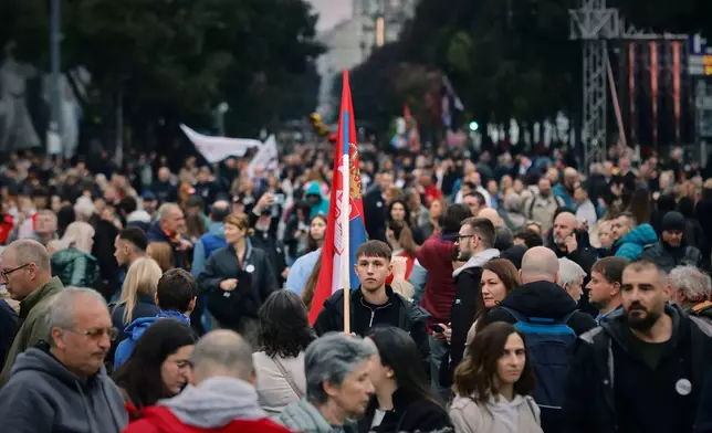 A young man holds a Serbian flag as people gather for the final "Student List – Students Win" rally ahead of a parliamentary election in Belgrade, Serbia, Thursday, Oct. 22, 2026. (AP Photo/Marko Drobnjakovic)