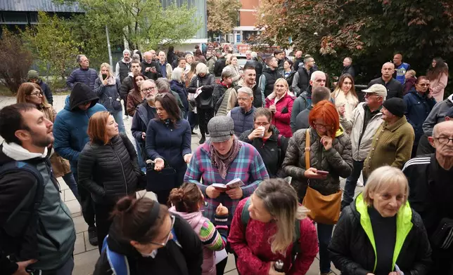 People wait outside a polling station before the start of voting in a parliamentary election in Novi Sad, Serbia, Sunday, Oct. 25, 2026. (AP Photo/Armin Durgut)