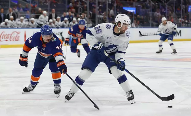 Tampa Bay Lightning's Brandon Hagel (38) skates with the puck against New York Islanders' Jean-Gabriel Pageau (44) during the first period of an NHL hockey game, Saturday, Oct. 10, 2026, in Elmont, N.Y. (AP Photo/Pamela Smith)