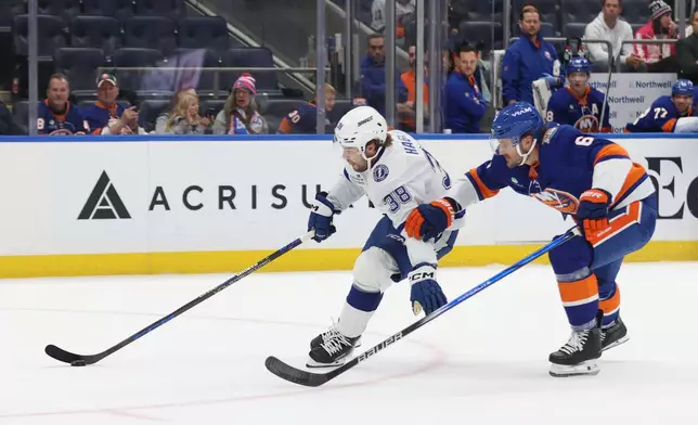 Tampa Bay Lightning's Brandon Hagel, left, skates with the puck against New York Islanders' Ryan Pulock, right, during the first period of an NHL hockey game, Saturday, Oct. 10, 2026, in Elmont, N.Y. (AP Photo/Pamela Smith)