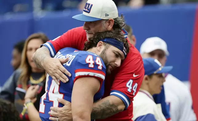 New York Giants running back Cam Skattebo (44) gets a hug from his father Leonard Skattebo prior to an NFL football game against the Arizona Cardinals, in East Rutherford, N.J., Sunday, Oct. 4, 2026. (AP Photo/Adam Hunger)