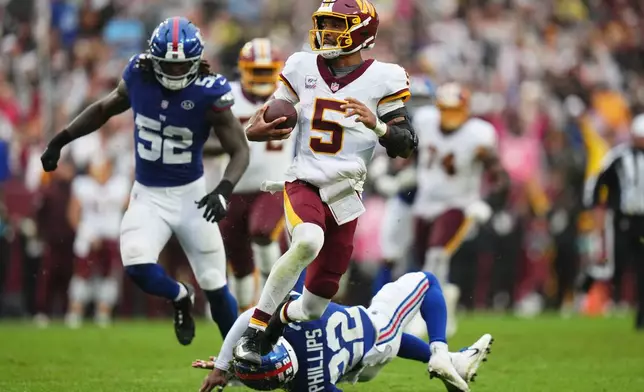 Washington Commanders quarterback Jayden Daniels (5) runs away from New York Giants' Arvell Reese (52) and Dru Phillips (22) for a touchdown during the second half of an NFL football game in Landover, Md., Sunday, Oct. 11, 2026. (AP Photo/Stephanie Scarbrough)