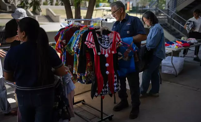 Samuel Hernandez, center, looks for a costume for his grandson during a Halloween costume swap at Occidental College in Los Angeles, Friday, Oct. 16, 2026. (AP Photo/Jae C. Hong)