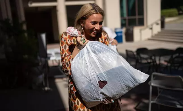 Sustainable fashion advocate Lexy Silverstein smiles while carrying a bag of costumes dropped off for a Halloween costume swap at Occidental College in Los Angeles, Friday, Oct. 16, 2026. (AP Photo/Jae C. Hong)