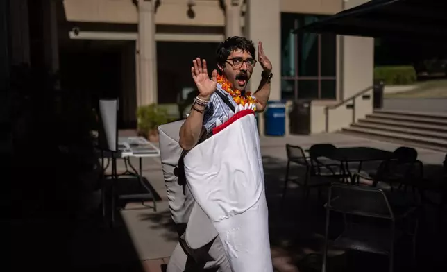 Braddock Sandoval, a chemistry professor at Occidental College, poses for photos with a costume he picked out during a Halloween costume swap on the campus in Los Angeles, Friday, Oct. 16, 2026. (AP Photo/Jae C. Hong)