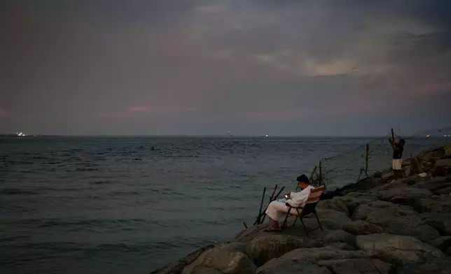 A man sits in a chair on a breakwater overlooking the Arabian Gulf in Dubai, United Arab Emirates, Thursday, Oct. 29, 2026. (AP Photo/Altaf Qadri)