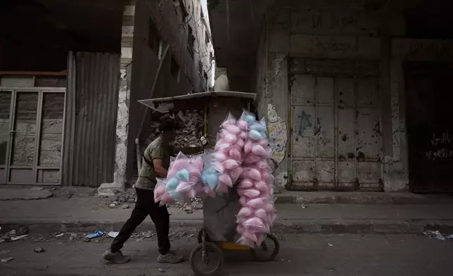 A Palestinian cotton candy vendor pushes his cart through Gaza City Wednesday, Oct. 28, 2026. (AP Photo/Jehad Alshrafi)
