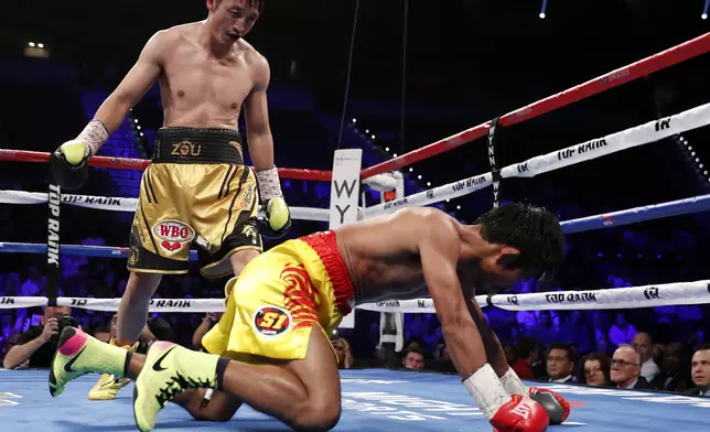 Zou Shiming, of China, stands over Prasitak Phaprom, of Thailand, during their WBO flyweight title boxing match Saturday, Nov. 5, 2016, in Las Vegas. Zou won by unanimous decision. (AP Photo/Isaac Brekken)