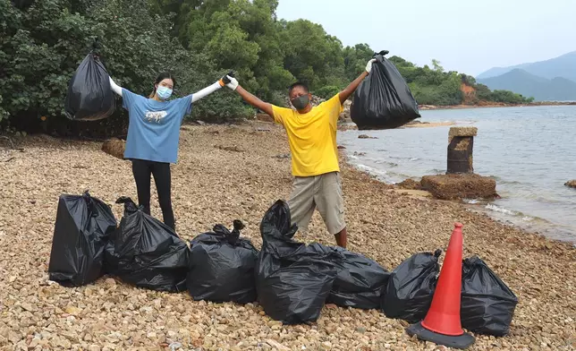 「貓哥」冼力求（右）與少女義工Belle（左）日前在大埔白沙頭洲海岸撿拾垃圾，為保護環境出一分力。