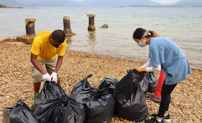 「貓哥」冼力求（左）與少女義工Belle（右）日前在大埔白沙頭洲海岸撿拾垃圾。