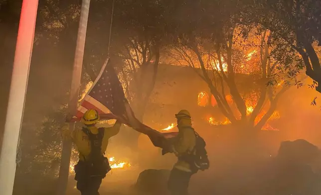 在一棟被燒毀的建築物外，消防隊員搶救一面美國國旗，被民眾稱讚為真英雄。網上圖片